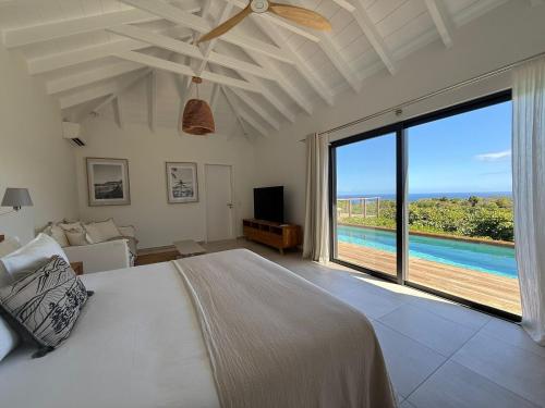 a bedroom with a bed and a large window at Spacious Modern Villa with Pool & Sunrise View - Graviola St Barth in Marigot