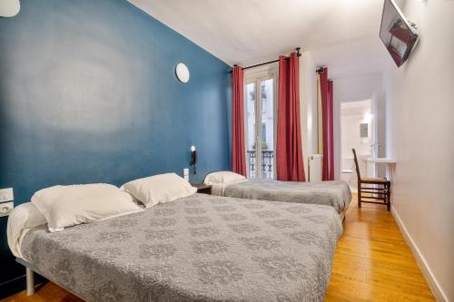 a bedroom with two beds and a blue wall at Hotel de Nantes in Paris