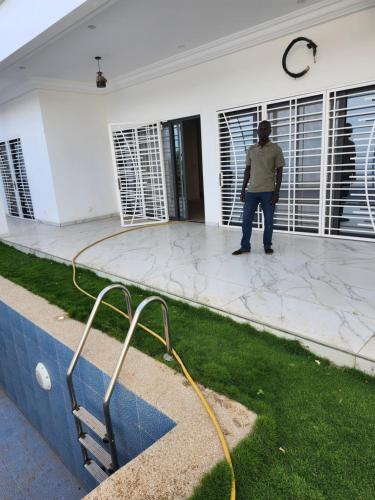 Un hombre parado afuera de un edificio con una manguera en Kird, en Ngaring
