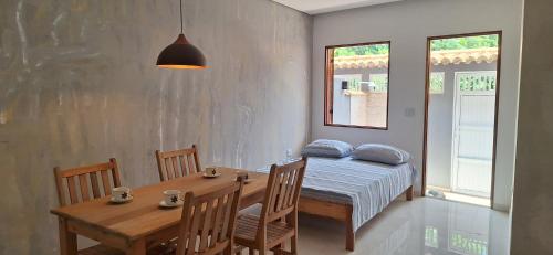 a dining room with a table and a bed and windows at Chalé Encanto Paraty in Paraty