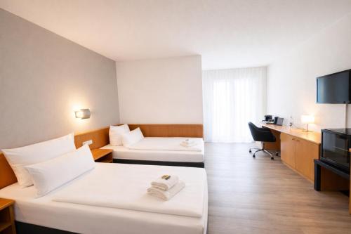a hotel room with two beds and a television at The Business Loft in Wolfsburg