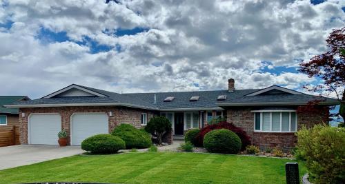 a brick house with a yard with green grass at Lake and the City Bed and Breakfast in West Kelowna