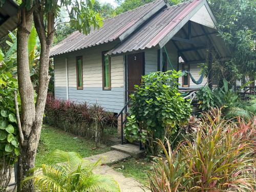a small white house with a tin roof at Green Garden Bungalow Resort in Ban Khlong Kloi