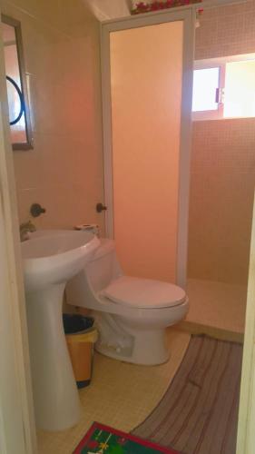 a bathroom with a white toilet and a sink at Hotel Ricarda Yopes Acapulco in Acapulco