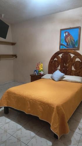 a bedroom with a large bed with a orange bedspread at Hotel Ricarda Yopes Acapulco in Acapulco