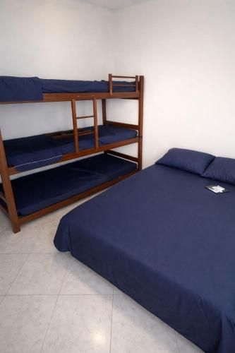 a bedroom with two bunk beds with blue sheets at Cantinho dos netos-suites próximo ao Sesc em Bertioga in Bertioga
