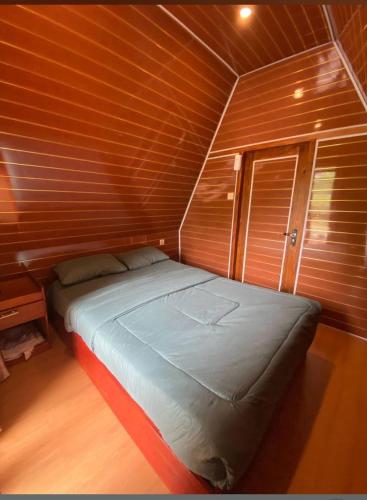 a bed in a room with a wooden wall at VILA RINJANI PARADAIS IIn in Sajang