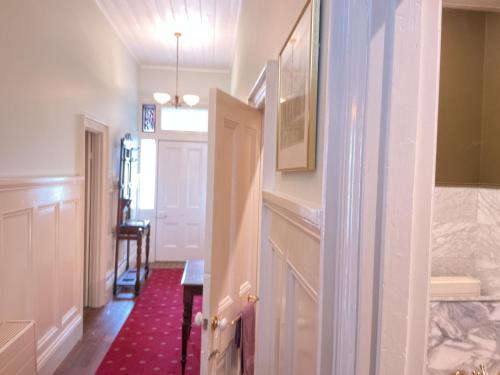 a hallway with a white door and a red rug at Bromwich Guest House - 250m to town centre! in Blackwood