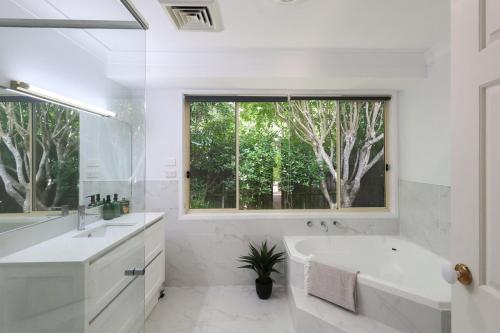 a white bathroom with a tub and a window at Linden Getaway Bowral in Bowral