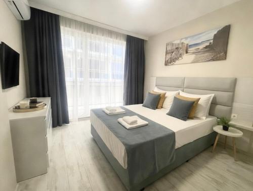 a bedroom with a large bed and a large window at ESKADA Apartments in Ahtopol