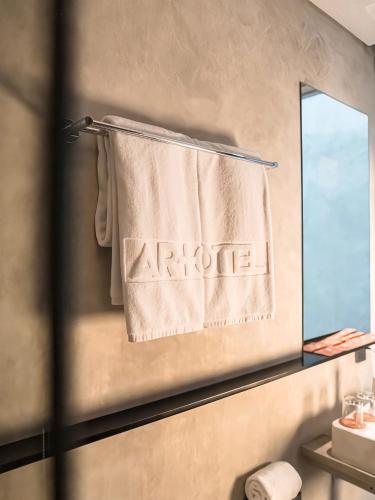 a bathroom with a towel with the word arote on a mirror at Maisola by ARTOTEL Semarang in Semarang