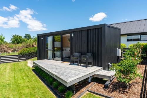 a black tiny house with a wooden table and chairs at Thomson's Nook - Taupo in Taupo