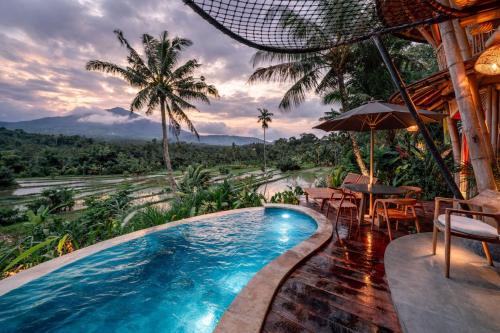 a pool in a resort with a table and chairs at Jiva Bali - Inaya in Selat