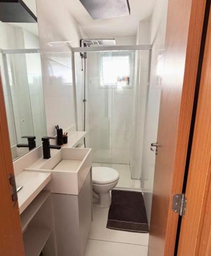 a white bathroom with a toilet and a shower at Lindo Apê Canto do Forte com lazer completo in Praia Grande