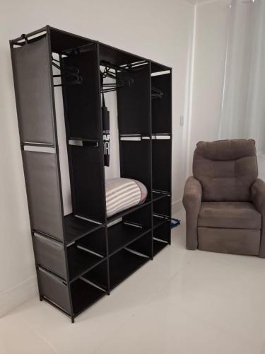 a black book shelf with a chair in a room at Recanto do Sol em Marica in Maricá