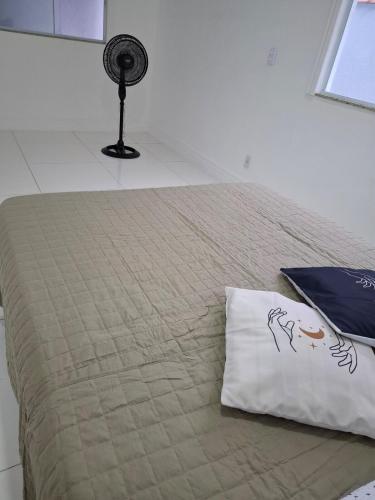 a bedroom with a bed with a pillow and a fan at Recanto do Sol em Marica in Maricá