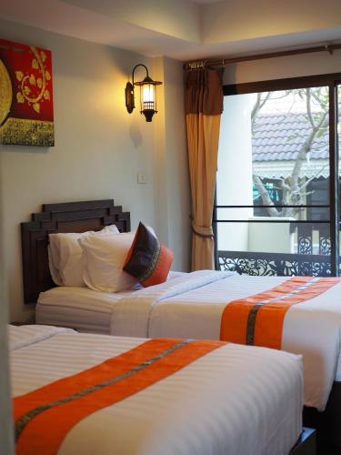 a hotel room with two beds and a window at Luckswan Resort Chiang Rai - SHA Extra Plus in Chiang Rai