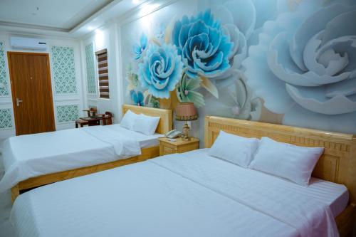 two beds in a room with blue flowers on the wall at An Gia Hotel in Quy Nhon