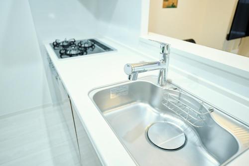 a kitchen sink with a faucet next to a stove at CREST Nishijin by Tranova in Fukuoka