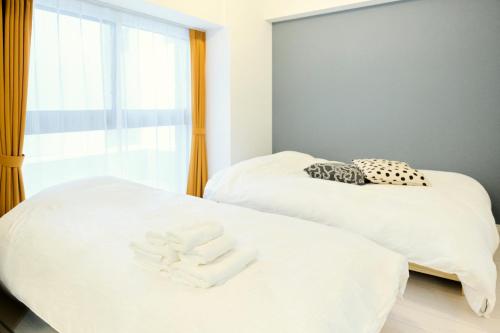 two beds with towels on them in a room at CREST Nishijin by Tranova in Fukuoka