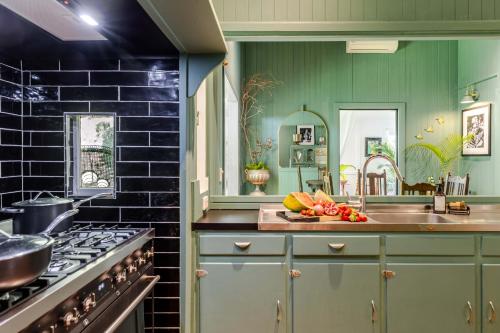 a kitchen with green cabinets and a sink at Charming Queenslander surrounded by Rainforest in Port Douglas
