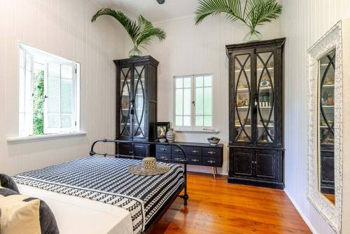 a bedroom with a bed and a dresser and two plants at Charming Queenslander surrounded by Rainforest in Port Douglas