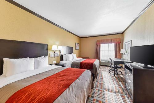 a hotel room with two beds and a flat screen tv at Quality Inn & Suites Lubbock South in Lubbock