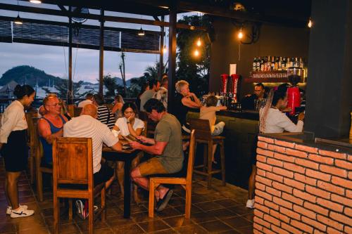 a group of people sitting at a bar at The Loft by Smoke House - Central Stay - Stairs Access in Labuan Bajo