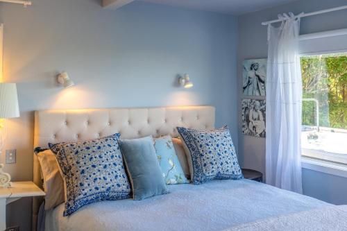 a bedroom with a bed with blue walls and a window at L'Appartement Bleu in Waiheke Island