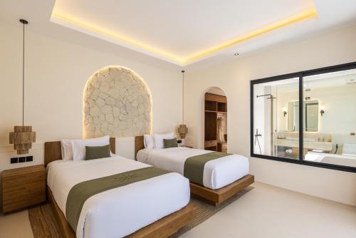 two beds in a hotel room with a bathroom at Solaya Villas Canggu in Canggu