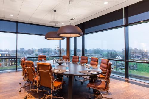 a conference room with a table and chairs and large windows at Van der Valk hotel Veenendaal in Veenendaal