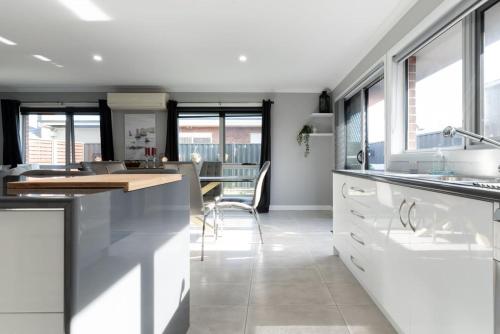 a kitchen with white cabinets and a dining room at Happy Tails Devonport in Devonport