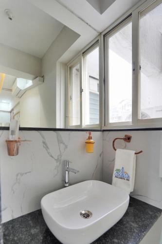 a white sink in a bathroom with a window at Hotel Palmera Inn in Pune
