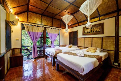 a bedroom with two beds with purple curtains at Marisa Resort & Spa Chiang Dao in Ban Muang Ngai