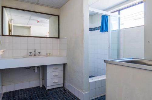a bathroom with a sink and a mirror and a tub at 1 Still Breeze in Maroochydore