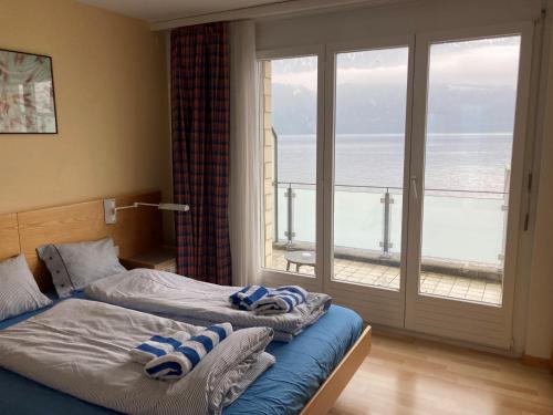 two beds in a bedroom with a view of the ocean at Gersau Hotel Fähri in Gersau