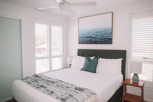 a white bedroom with a bed and two windows at Salt @ South West Rocks in South West Rocks