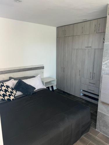 a bedroom with a black bed and wooden cabinets at comfortable and nice loft, great location in Aguascalientes