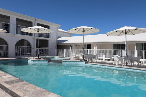 a swimming pool with chairs and umbrellas next to a building at Don Pancho Beach Resort in Bargara
