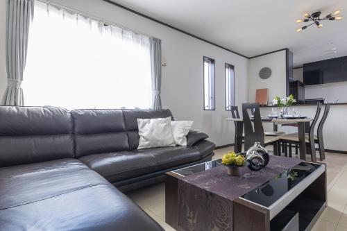a living room with a black leather couch and a table at A Family Friendly Spacious Villa - Easy to Tokyo Station & Conveniently Located for Tokyo Disney Resort & 1 min to Convenience Store in Tokyo