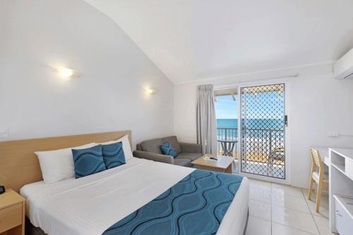 a bedroom with a bed and a view of the ocean at Don Pancho Beach Resort in Bargara
