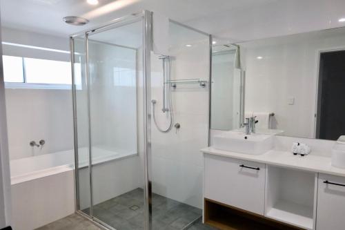 a bathroom with a glass shower and a sink at Don Pancho Beach Resort in Bargara
