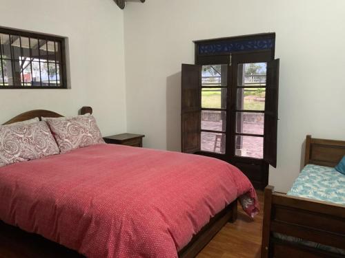 a bedroom with a red bed and two windows at Finca San Pablo in Subachoque