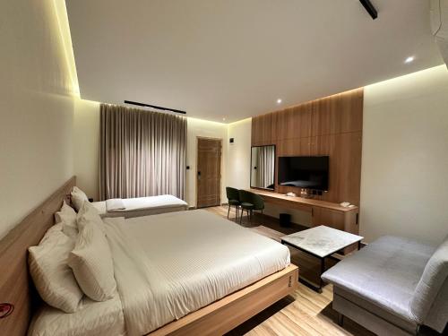 a bedroom with a bed and a desk and a television at Hamsun Shahrah-e-Faisal Extension in Karachi