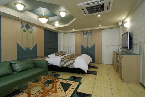a bedroom with a bed and a couch and a tv at ホテル アイアンプレミアム 西宮北店 男塾ホテルグループ in Nishinomiya