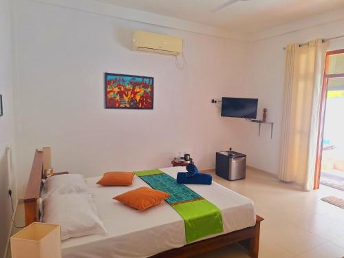 a bedroom with a bed and a tv on the wall at Coconut Villa in Bentota