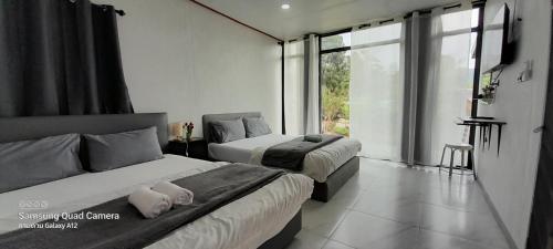 a bedroom with two beds and a large window at lnthanon Laoju เล่าจู in Ban Na Yang
