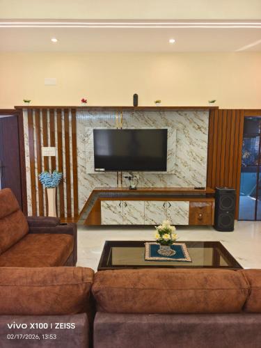 a living room with a couch and a flat screen tv at YELAGiRI GRAND PALACE in Yelagiri