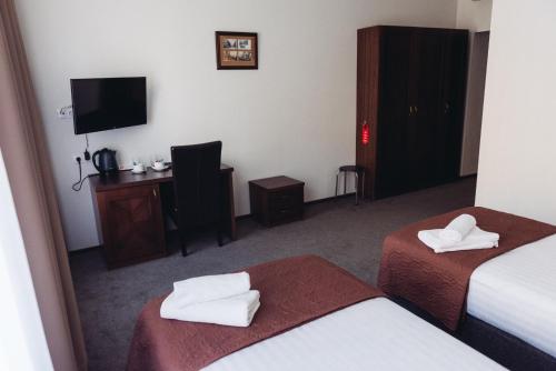 a hotel room with two beds and a television at Biplan City in Daugavpils