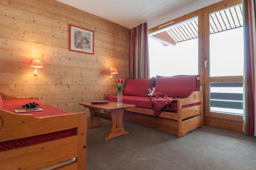 un salon avec un canapé rouge et une table dans l'établissement Quartier Crève Cœur - maeva Home, à Valmorel